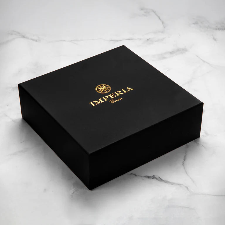A black Imperia caviar gift box on a marble surface