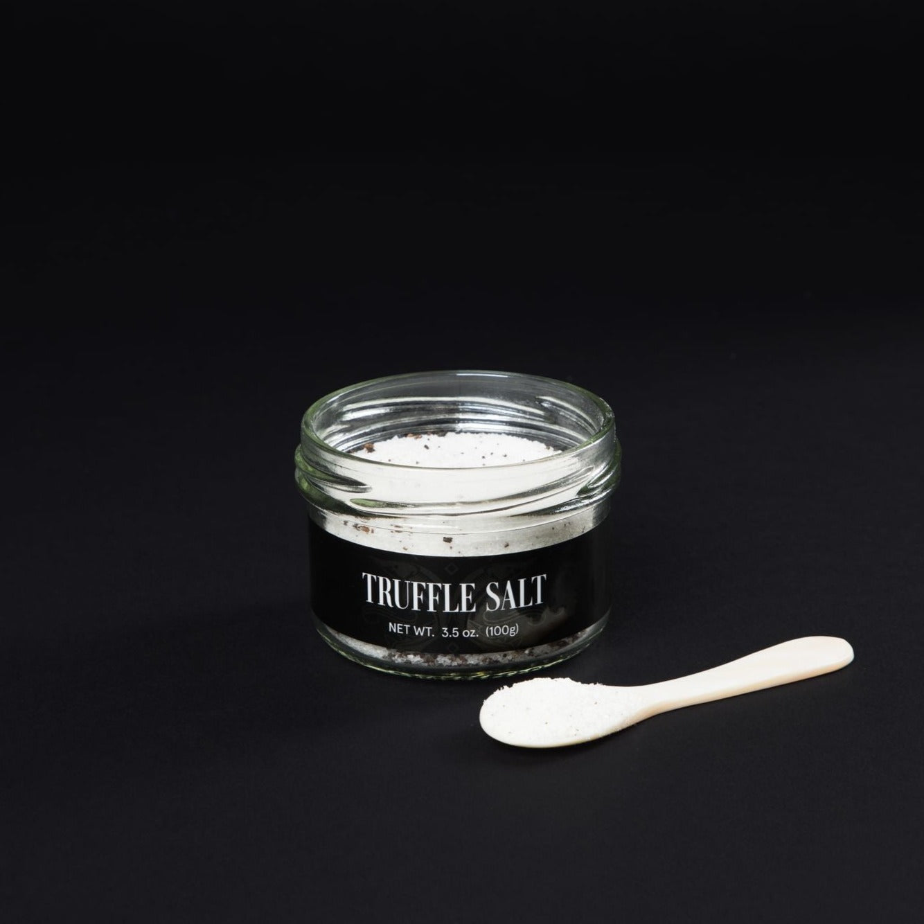 an open Imperia caviar truffle salt bottle next to a mother-of-pearl-spoon